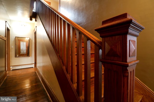 stairs featuring wood-type flooring and a baseboard heating unit