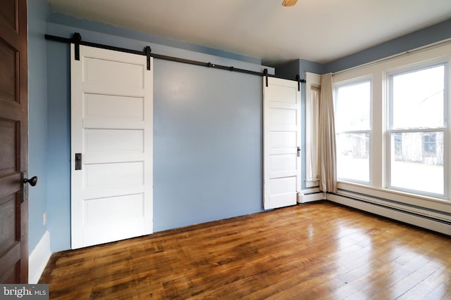 unfurnished bedroom featuring hardwood / wood-style floors and a barn door