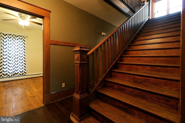 stairway with a healthy amount of sunlight, ceiling fan, wood-type flooring, and a baseboard heating unit