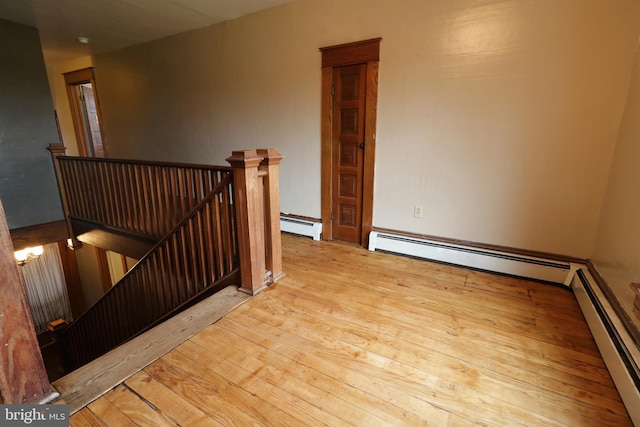 stairway featuring baseboard heating and hardwood / wood-style floors