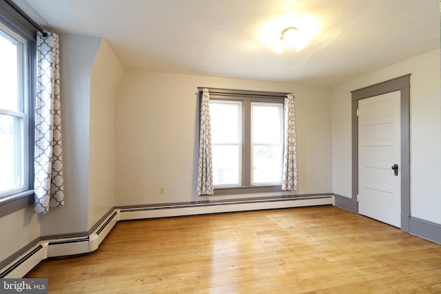 unfurnished bedroom featuring multiple windows, a baseboard radiator, and light wood-type flooring