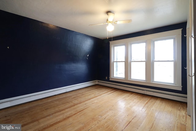 empty room with ceiling fan, wood-type flooring, and a baseboard heating unit