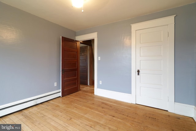 unfurnished bedroom with a baseboard radiator and light hardwood / wood-style flooring