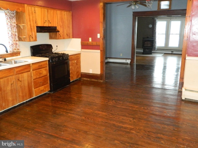 kitchen with sink, a baseboard radiator, black gas stove, dark hardwood / wood-style floors, and a wood stove