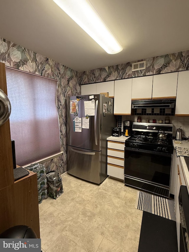 kitchen with stainless steel refrigerator, white cabinets, ventilation hood, and black gas range oven