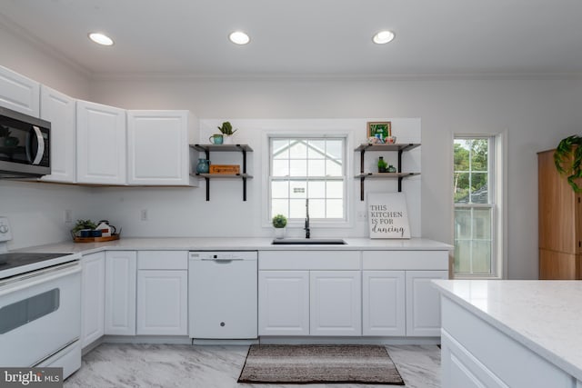 kitchen with white appliances, white cabinetry, plenty of natural light, and sink