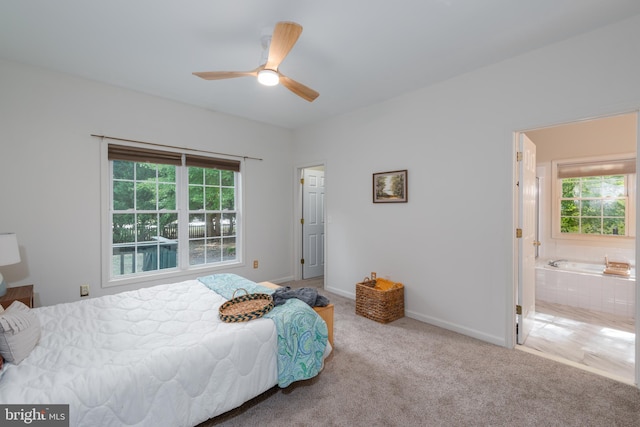 carpeted bedroom featuring multiple windows, ceiling fan, and ensuite bath