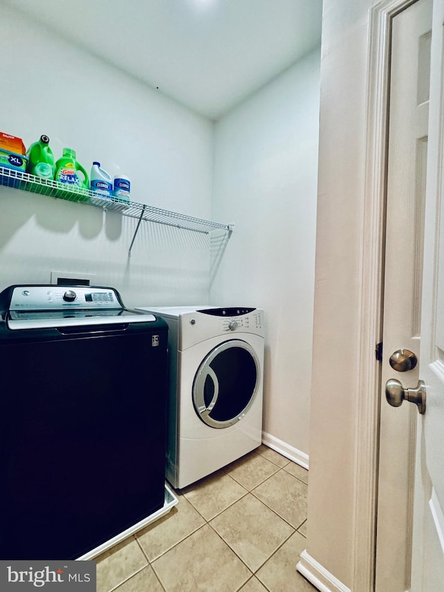 clothes washing area featuring washing machine and dryer and light tile patterned floors