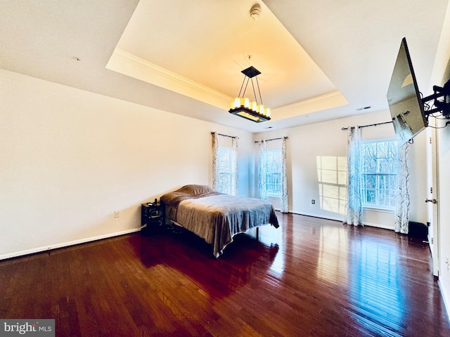 bedroom with dark wood-type flooring, a tray ceiling, and multiple windows