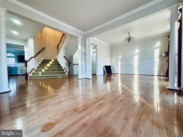 unfurnished living room featuring decorative columns, hardwood / wood-style floors, ornamental molding, and an inviting chandelier