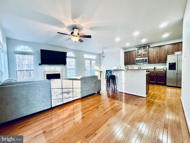 unfurnished living room with light wood-type flooring, a wealth of natural light, and ceiling fan