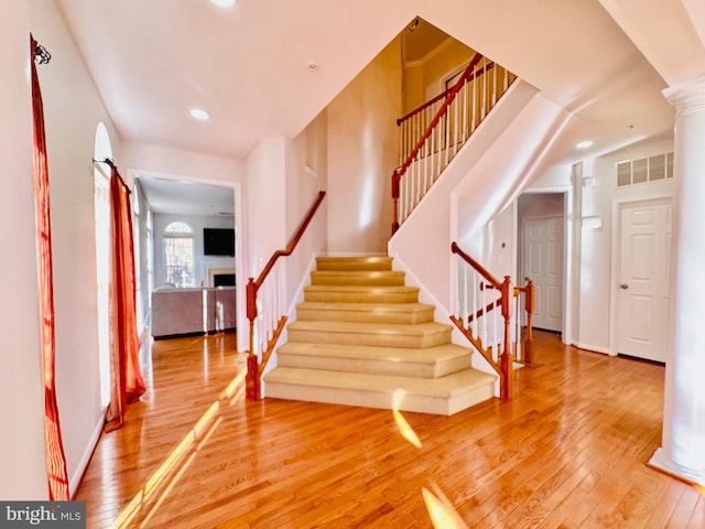 staircase with decorative columns and hardwood / wood-style flooring