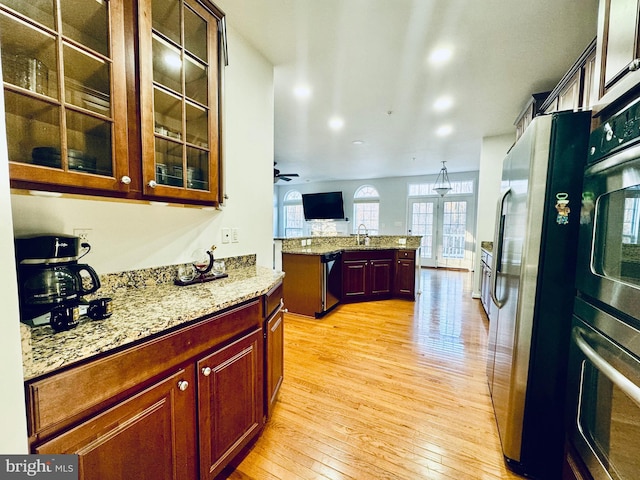 kitchen featuring sink, light hardwood / wood-style flooring, ceiling fan, appliances with stainless steel finishes, and light stone counters