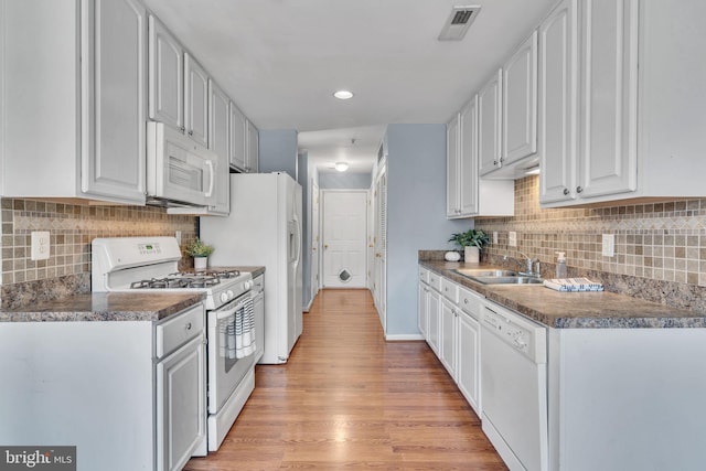 kitchen featuring decorative backsplash, light wood-type flooring, white appliances, sink, and white cabinets