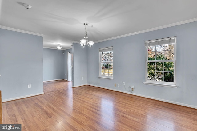 empty room with light wood-type flooring, an inviting chandelier, plenty of natural light, and ornamental molding