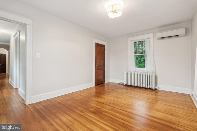1411 W St, Annapolis, MD 21401 - unfurnished room with light wood-style flooring, baseboards, a wall unit AC, and radiator heating unit