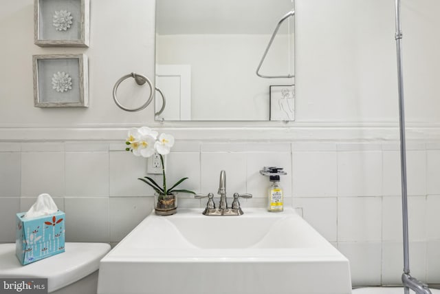 bathroom featuring toilet, sink, and tile walls