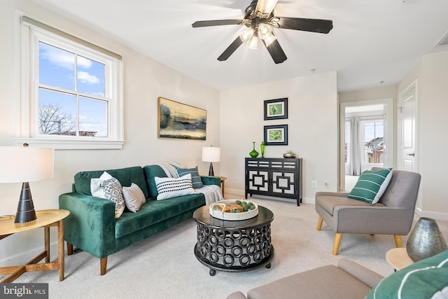 living room featuring light carpet, ceiling fan, and a healthy amount of sunlight