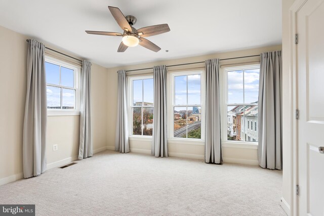 unfurnished room featuring light colored carpet and ceiling fan