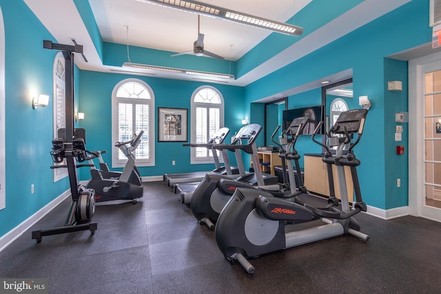 workout area with ceiling fan and a tray ceiling