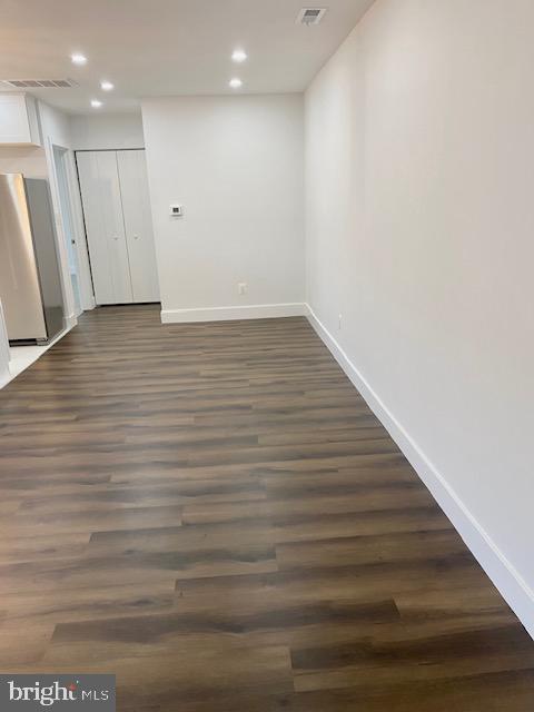 basement featuring stainless steel fridge and dark hardwood / wood-style flooring