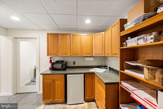 kitchen featuring a paneled ceiling, sink, and light carpet