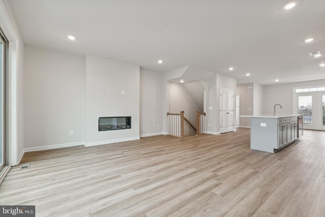 unfurnished living room with french doors, light hardwood / wood-style flooring, and sink