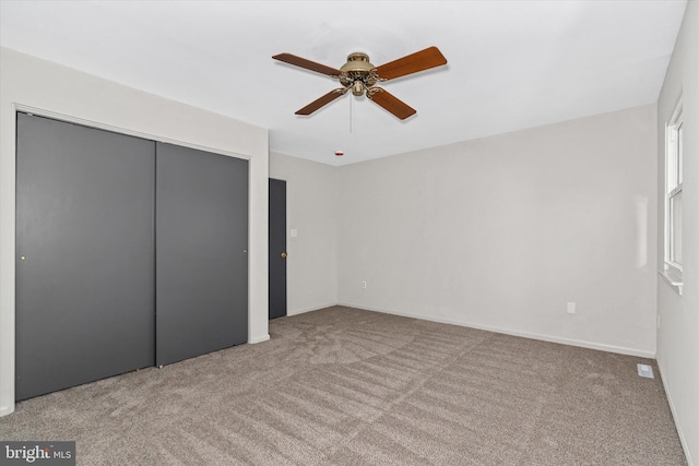 unfurnished bedroom with ceiling fan, light colored carpet, and a closet