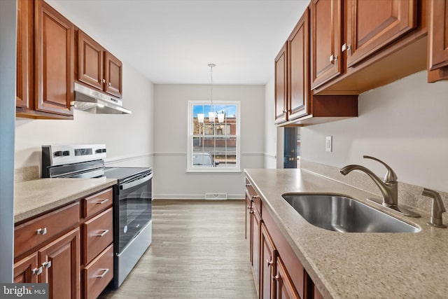 kitchen with electric range, sink, hanging light fixtures, a notable chandelier, and light hardwood / wood-style floors