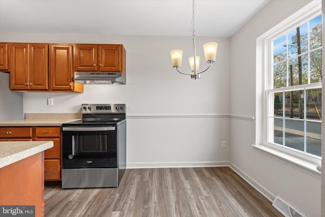 kitchen with stainless steel electric stove, a chandelier, pendant lighting, and hardwood / wood-style flooring