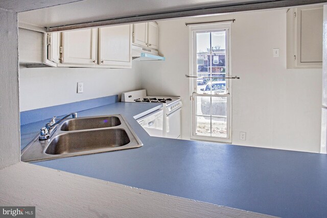 kitchen featuring sink, white cabinets, and white stove