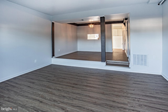 spare room with a chandelier and dark hardwood / wood-style floors