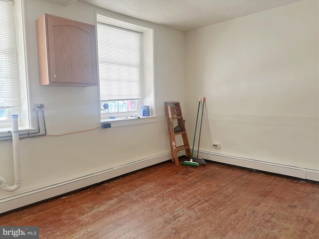 unfurnished room with baseboard heating and wood-type flooring