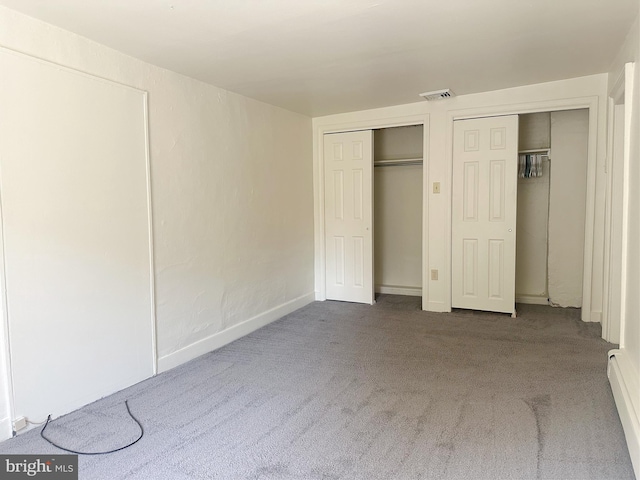 unfurnished bedroom with carpet floors and two closets