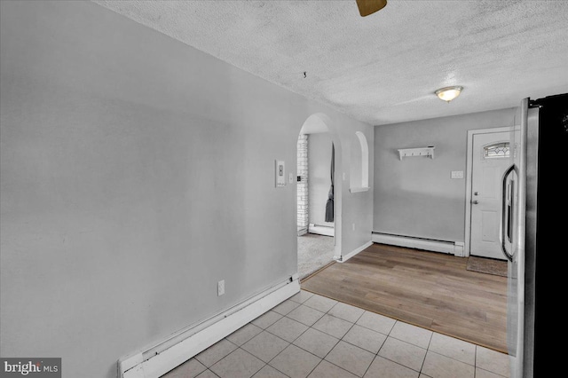 foyer entrance with a textured ceiling, light hardwood / wood-style flooring, and a baseboard heating unit