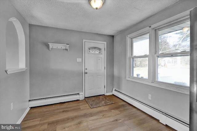 entrance foyer featuring baseboard heating, light hardwood / wood-style flooring, and a textured ceiling