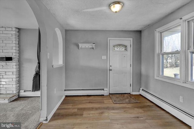 entryway with light hardwood / wood-style floors, a textured ceiling, and a baseboard heating unit