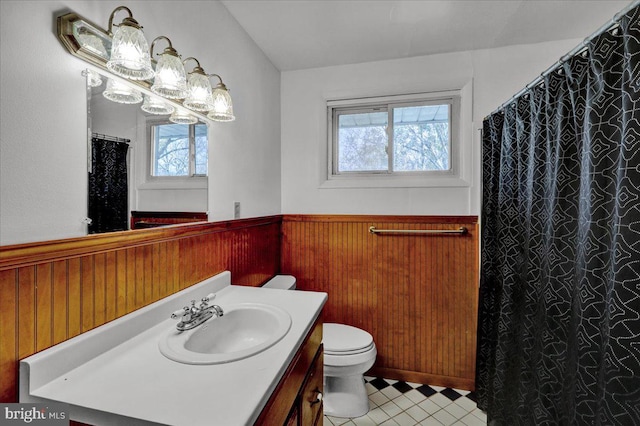 bathroom featuring tile patterned flooring, vanity, toilet, and wood walls