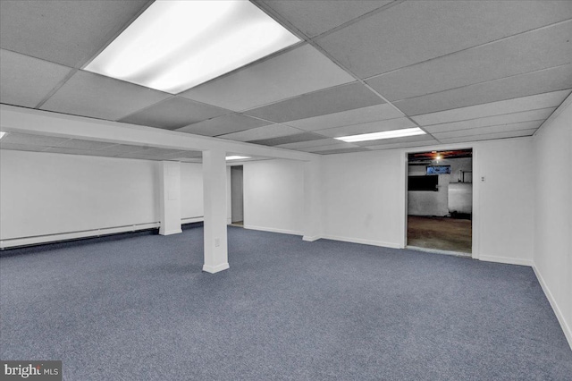 basement with dark colored carpet, a baseboard radiator, and a drop ceiling