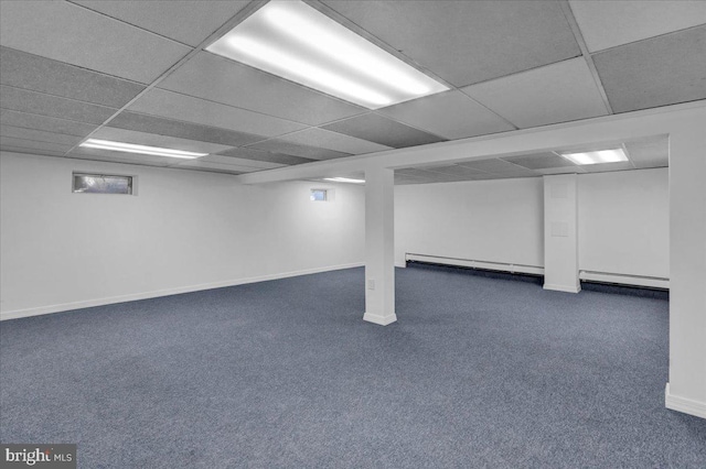 basement featuring dark colored carpet, a paneled ceiling, and baseboard heating