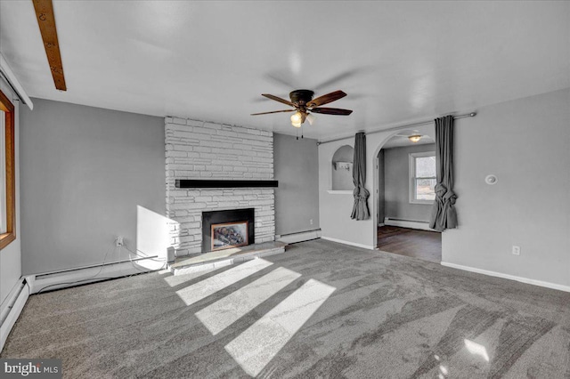 unfurnished living room featuring dark colored carpet, a fireplace, ceiling fan, and baseboard heating