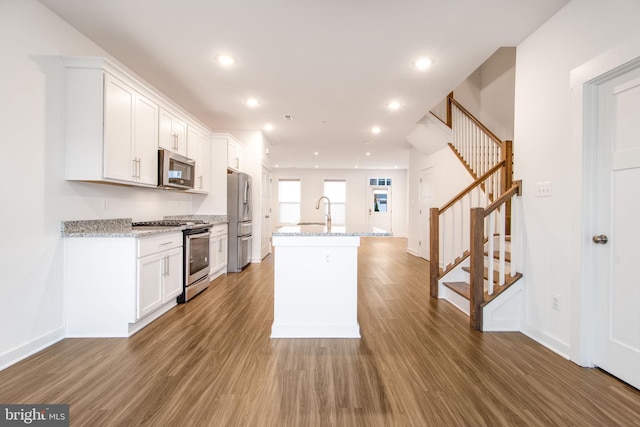 kitchen featuring white cabinets, dark hardwood / wood-style flooring, stainless steel appliances, and a kitchen island with sink