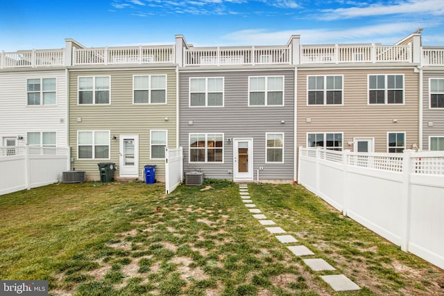 rear view of property featuring a yard and central air condition unit