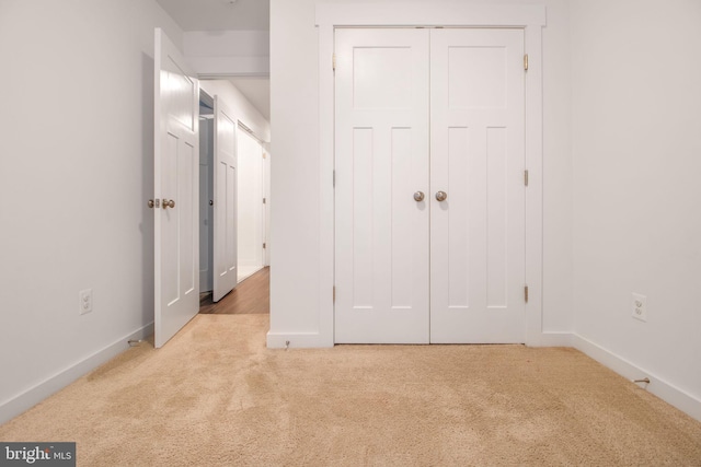 unfurnished bedroom featuring a closet and light colored carpet