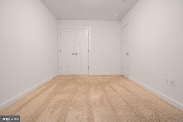 unfurnished bedroom with light carpet and a closet