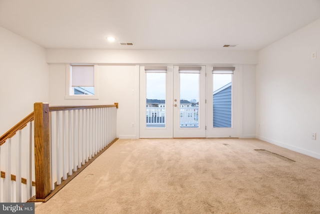 carpeted spare room featuring french doors