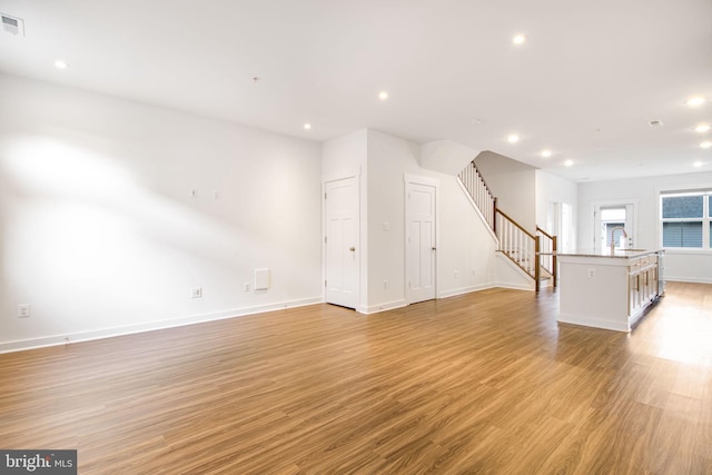 unfurnished living room with light hardwood / wood-style floors and sink