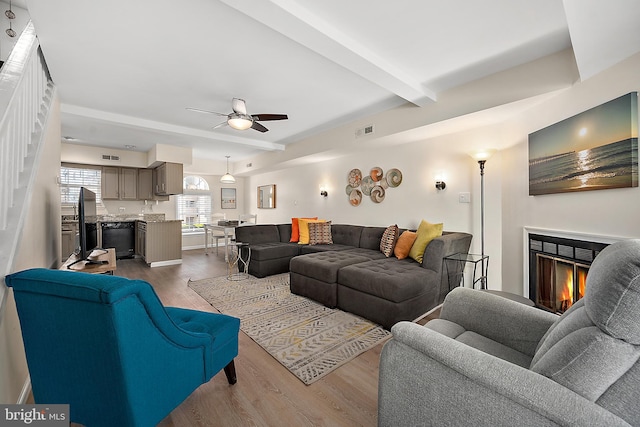 living room with ceiling fan, beam ceiling, and dark wood-type flooring