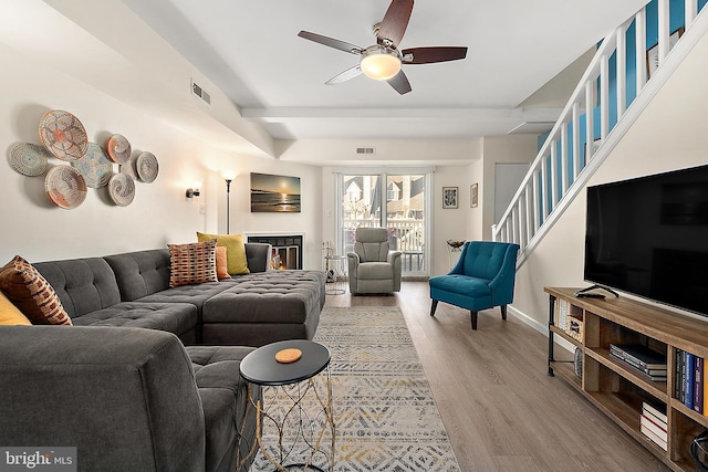 living room featuring hardwood / wood-style floors, ceiling fan, and a fireplace