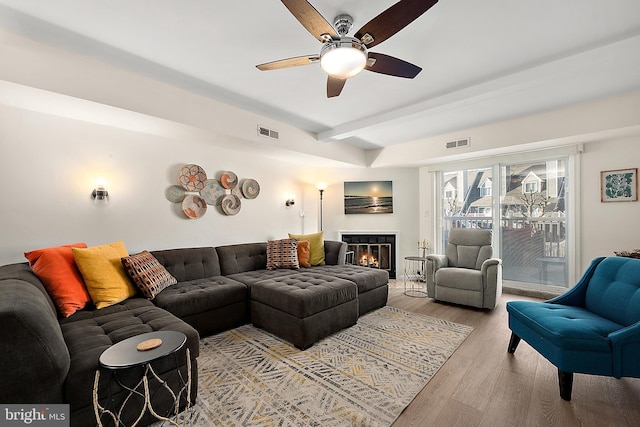 living room featuring beam ceiling, light hardwood / wood-style flooring, and ceiling fan